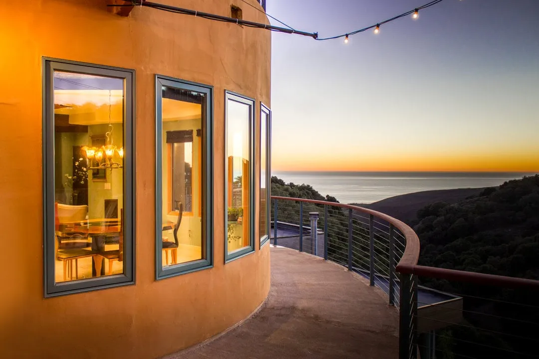 Pismo Beach House: curved glass wall and terrace overlooking the ocean at dusk